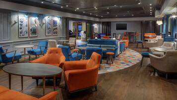 A modern lounge area with seating arrangements, a television, and artwork on the walls.