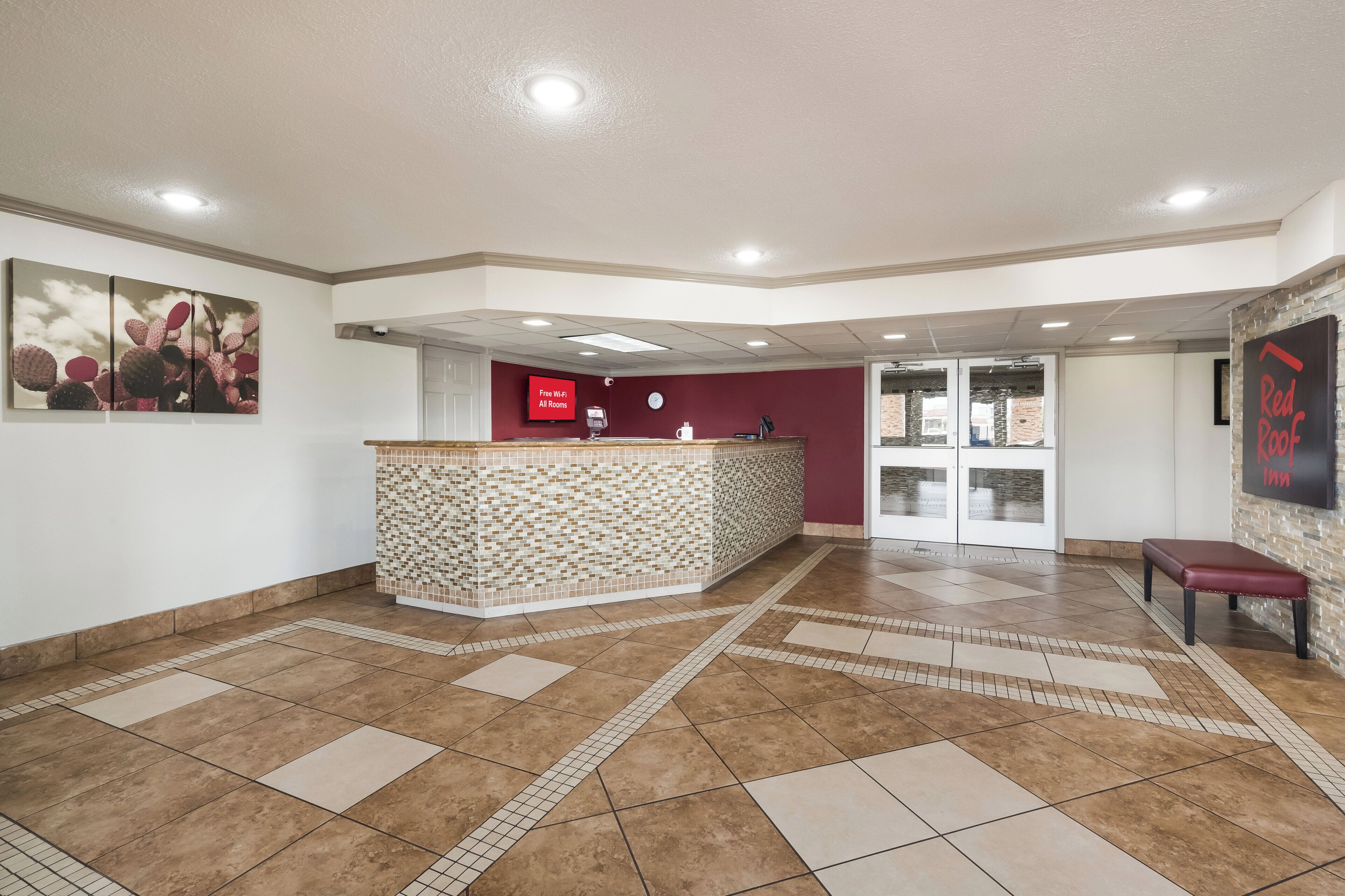 A hotel lobby with a reception desk, a clock, and a sign indicating free Wi-Fi.