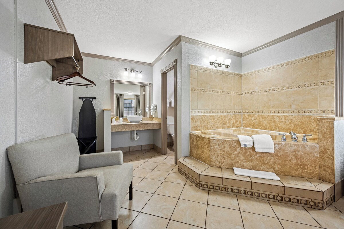 A modern bathroom with a large bathtub, a vanity with a mirror, and a seating area.