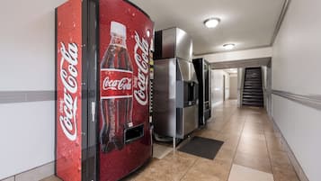A hallway with a vending machine and a refrigerator.