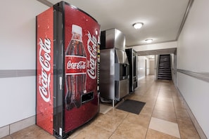A hallway with a vending machine and a refrigerator.