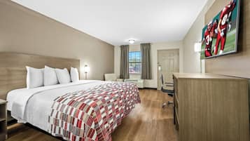 Een hotelkamer met een groot bed, een bureau, een flatscreen televisie en een raam met gordijnen.
