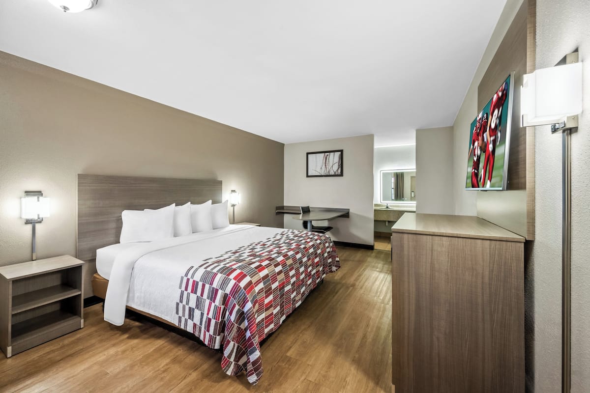 Een moderne hotelkamer met een groot bed, nachtkastjes, een bureau en een spiegel.