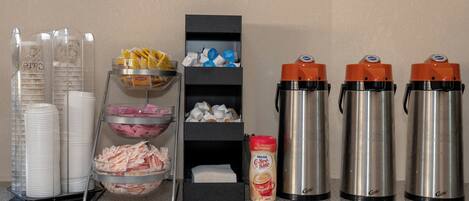 Montaje de bufé con platos apilados, tazones de comida y dispensadores de bebidas.