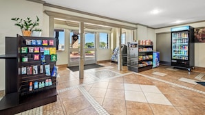 A clean, well-lit lobby with vending machines, a refrigerator stocked with snacks, and a potted plant. - Red Roof Inn College Station (College Station)