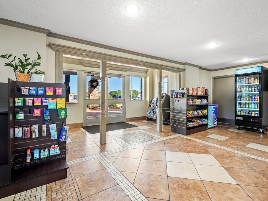 A clean, well-lit lobby with vending machines, a refrigerator stocked with snacks, and a potted plant.