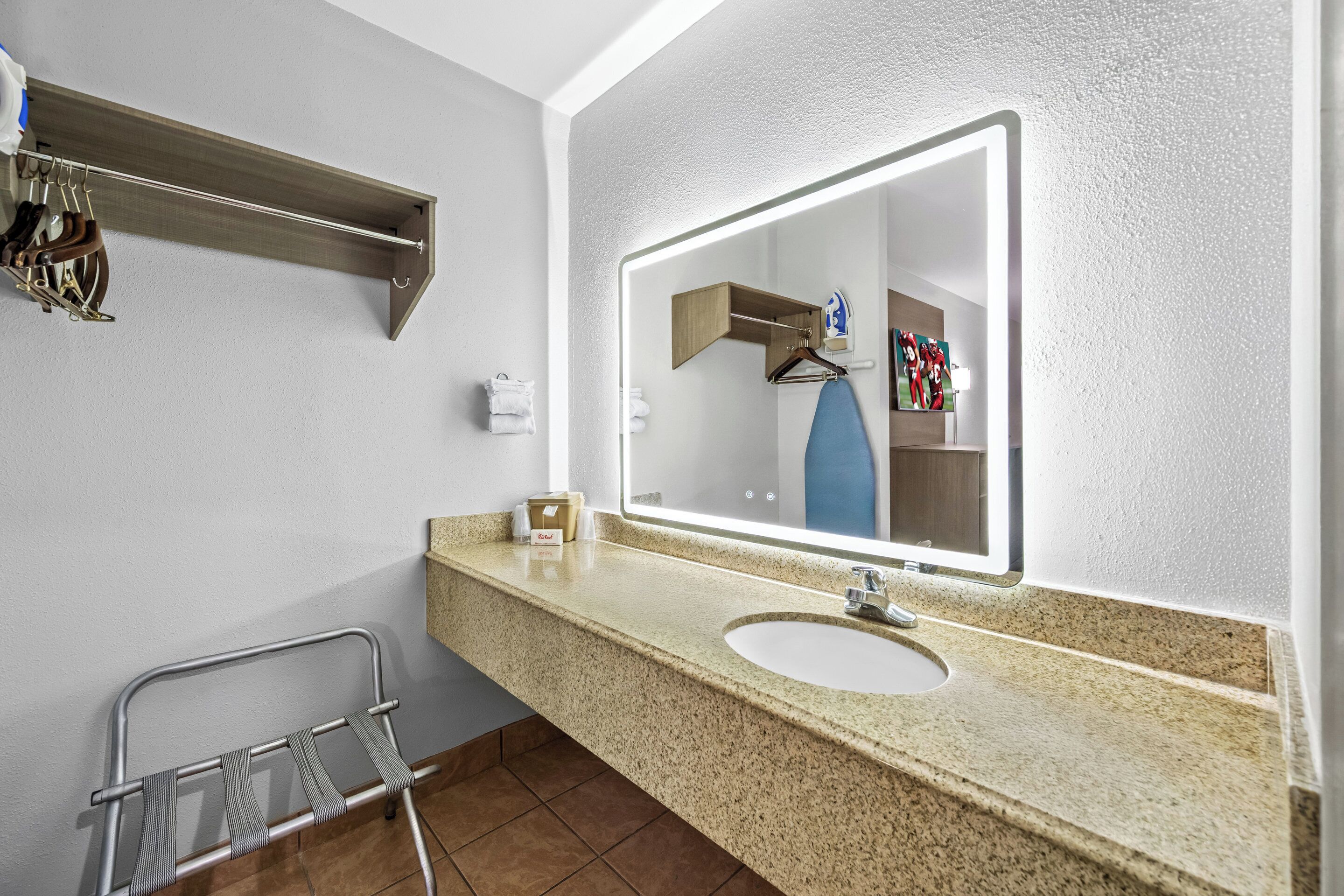 A bathroom with a granite countertop, a sink, a mirror, a towel rack, and a shower area.
