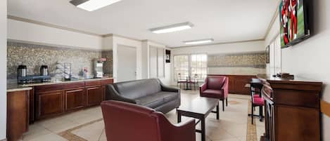 A modern kitchen with a built-in stove, a dining area with a table and chairs, and a living area with a sofa and chairs.