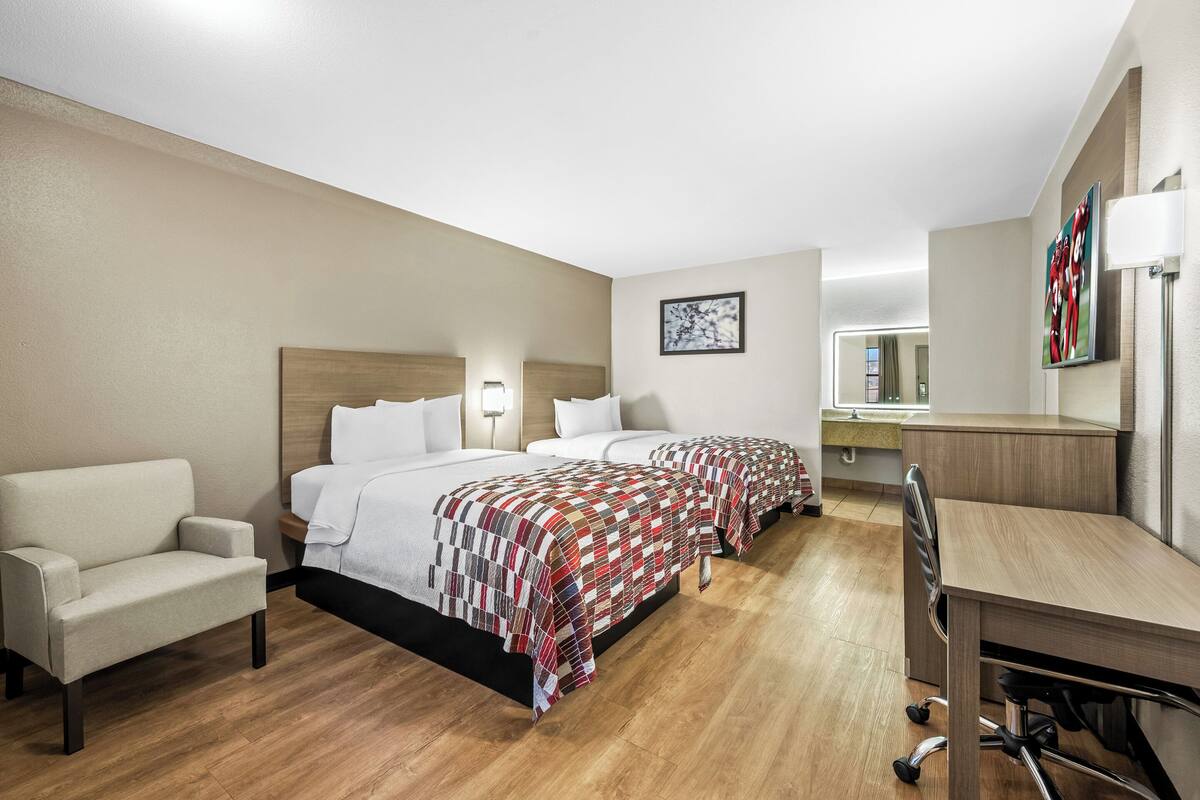 Een hotelkamer met een bed, een bureau, een stoel en een kleine bank.