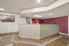 A reception area with a tiled counter, a digital screen displaying 'Free Wi-Fi All Rooms,' and a clock on the wall.