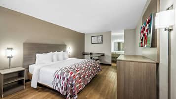 Una habitación de hotel moderna con una cama grande, mesitas de noche, un escritorio y un espejo.