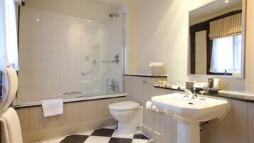 A bathroom with a shower, toilet, sink, and a mirror.