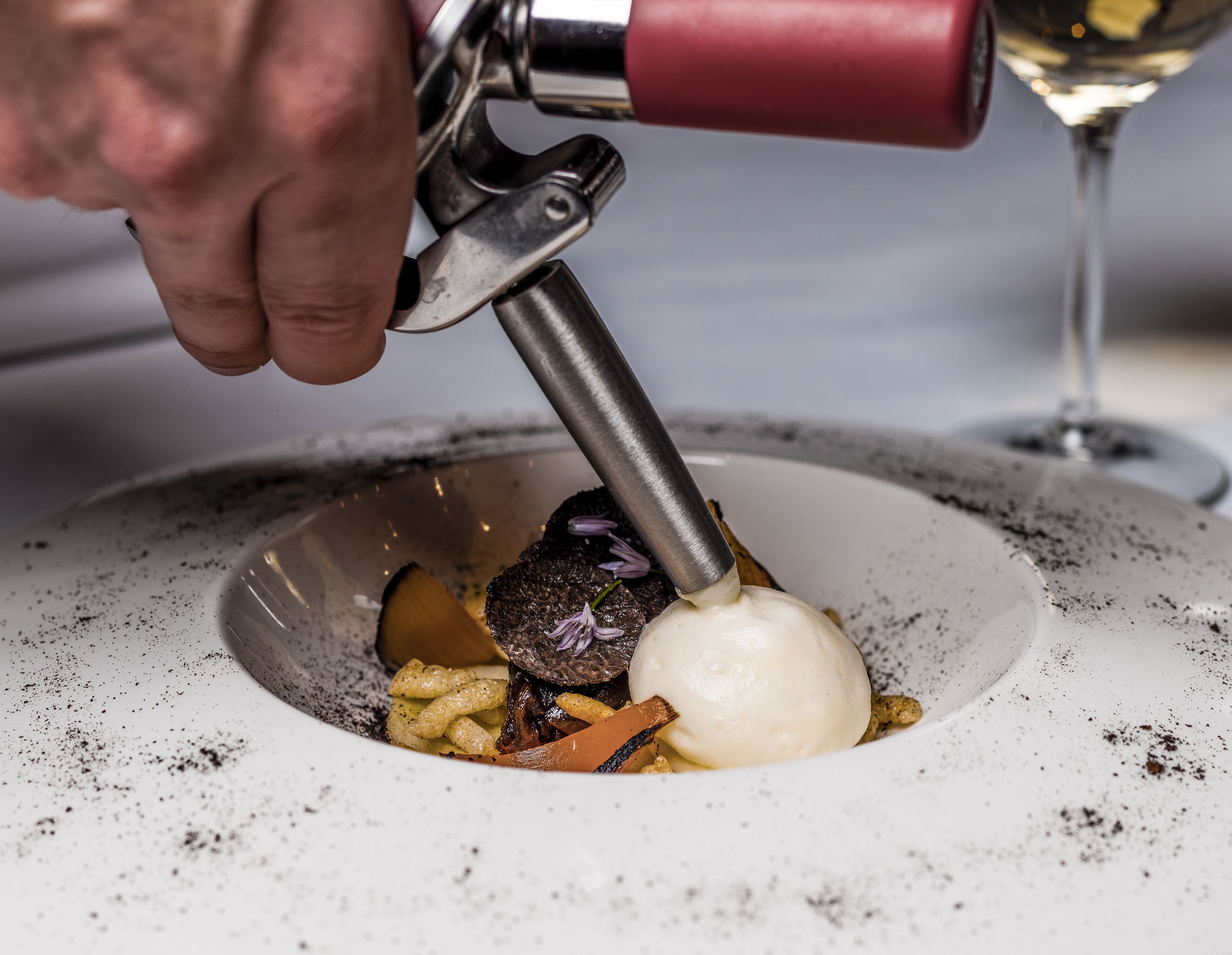 A person using a tool to prepare a dish on a white plate.