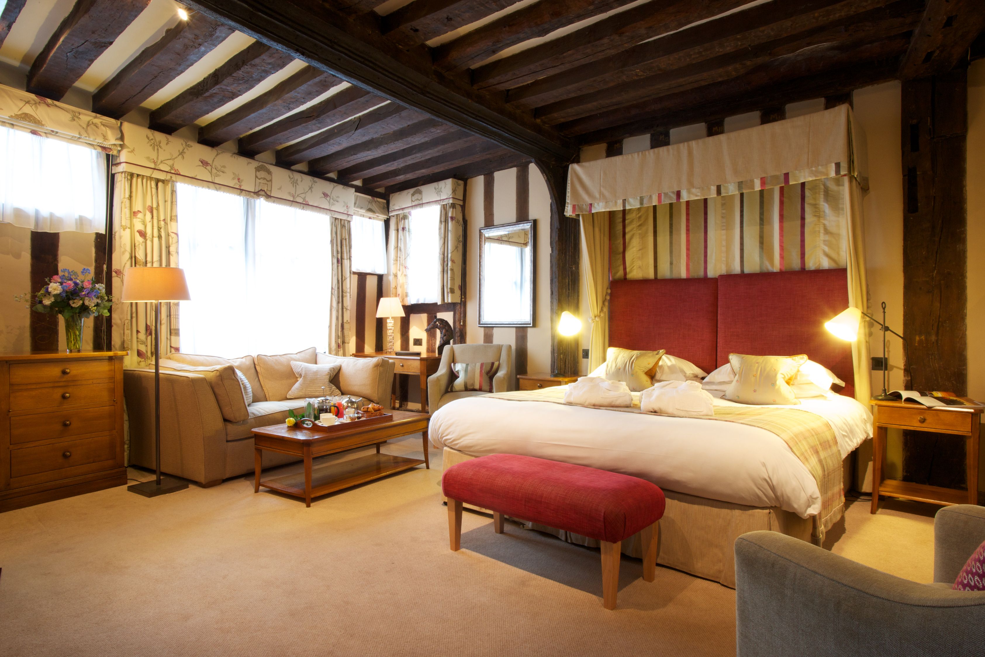A hotel room with a large bed, a sofa, a desk, and a chair.