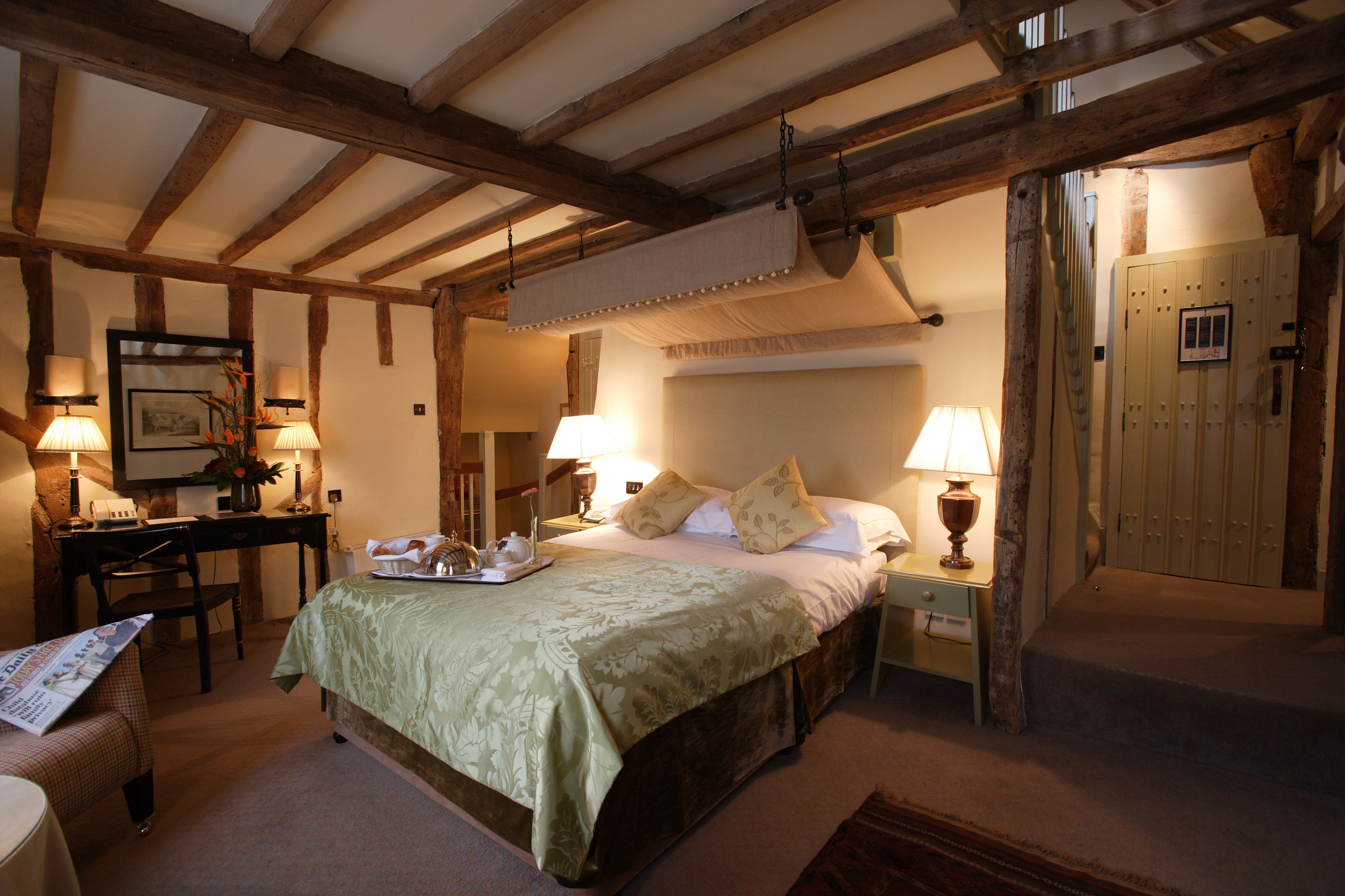 A bedroom with a bed, bedside tables, lamps, a desk, and a chair.