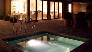 A swimming pool with a glass bottom, surrounded by a brick patio. - The Swan Hotel (Sudbury)
