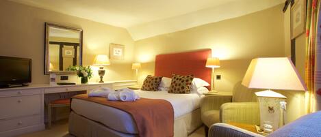 A hotel room with a bed, a desk, a television, a chair, and a lamp.
