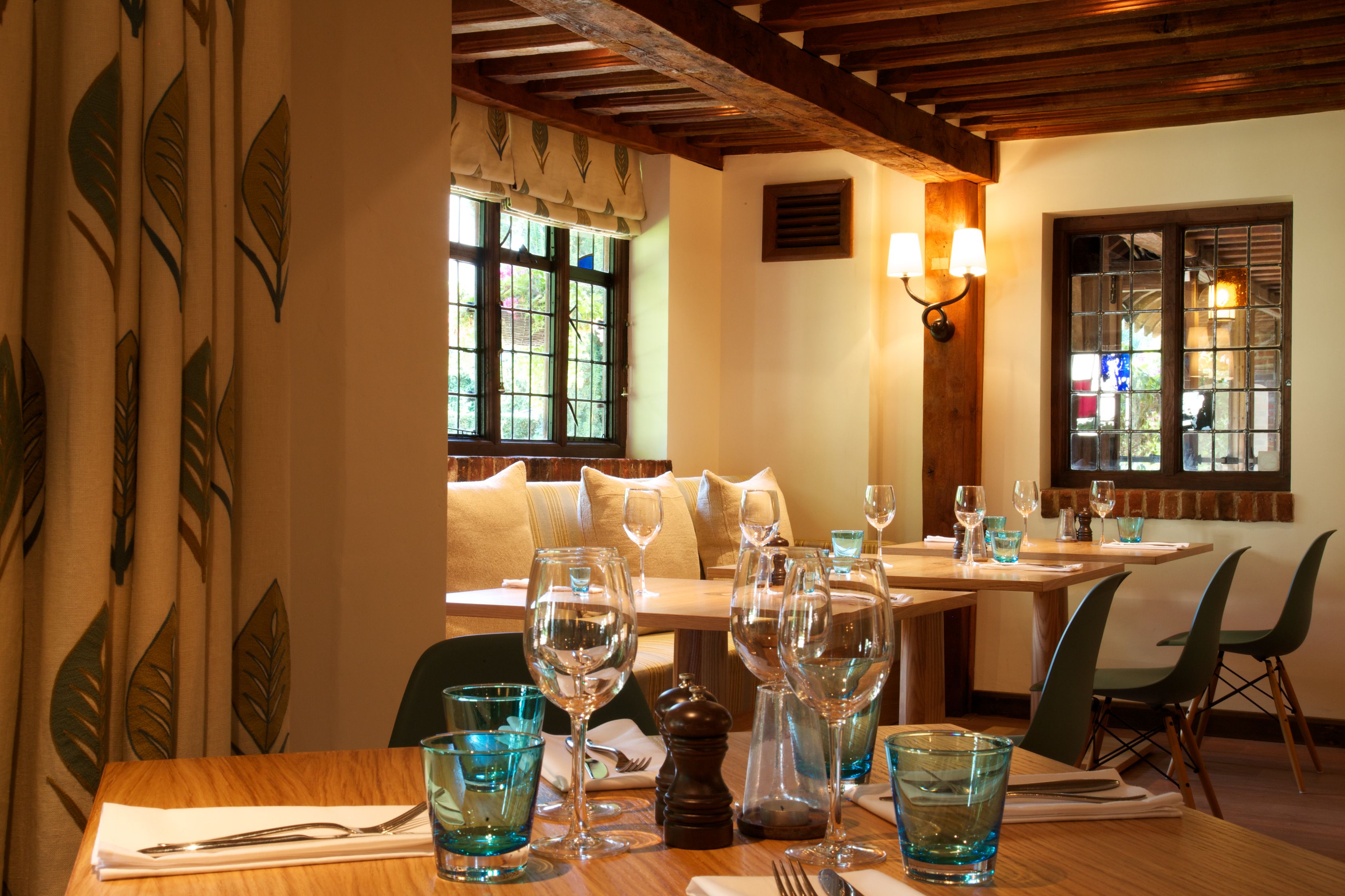 Comedor con mesas dispuestas para una comida, con cristalería y cubertería.