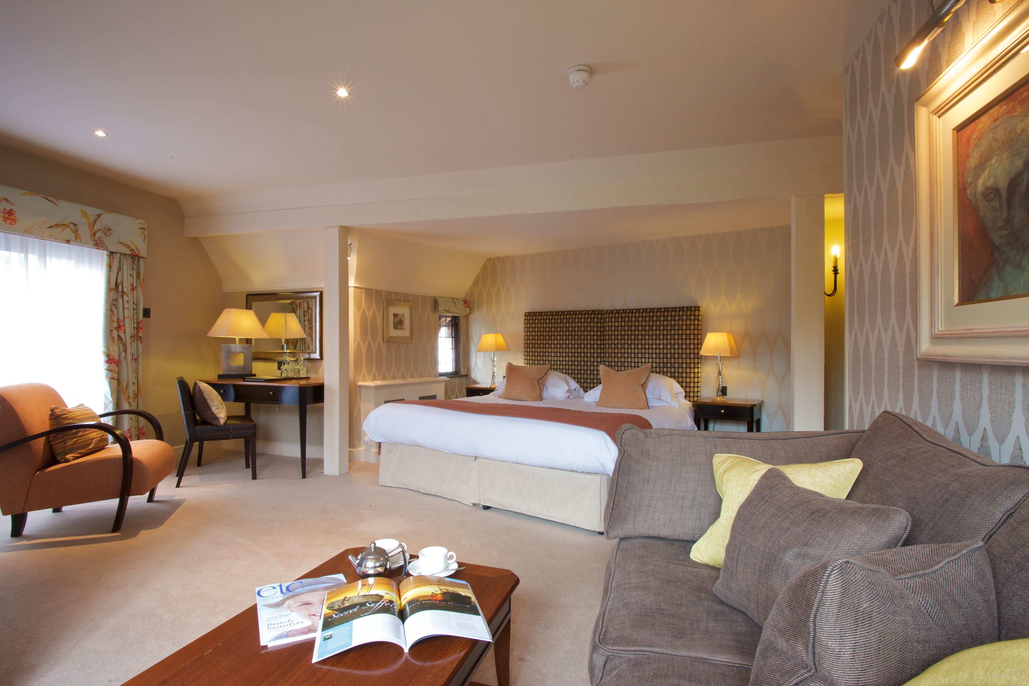 A hotel room with a bed, a sofa, a desk, and a chair.