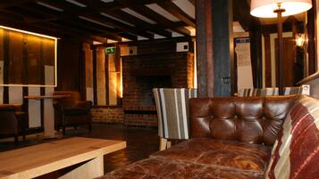 A cozy interior with a leather sofa, wooden tables, and a brick fireplace.