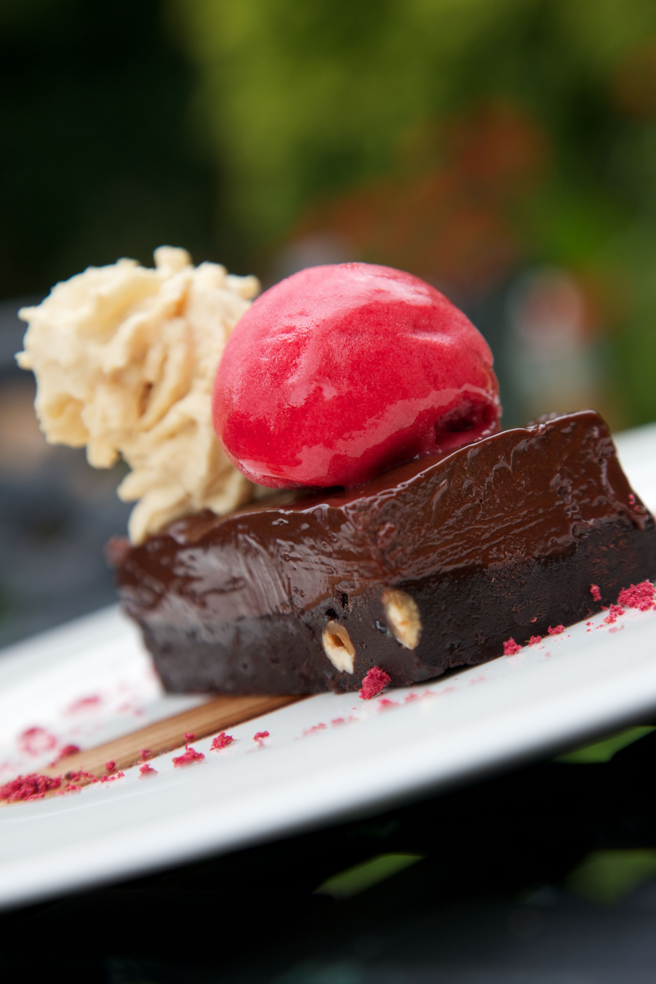 Un dessert composé d’une boule de glace rouge posée sur un brownie au chocolat.