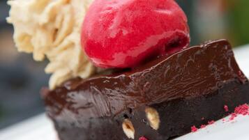 Un dessert composé d’une boule de glace rouge posée sur un brownie au chocolat.