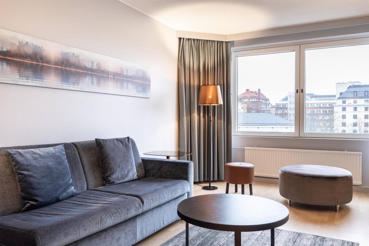 A modern living room with a grey sofa, a round coffee table, and a lamp.