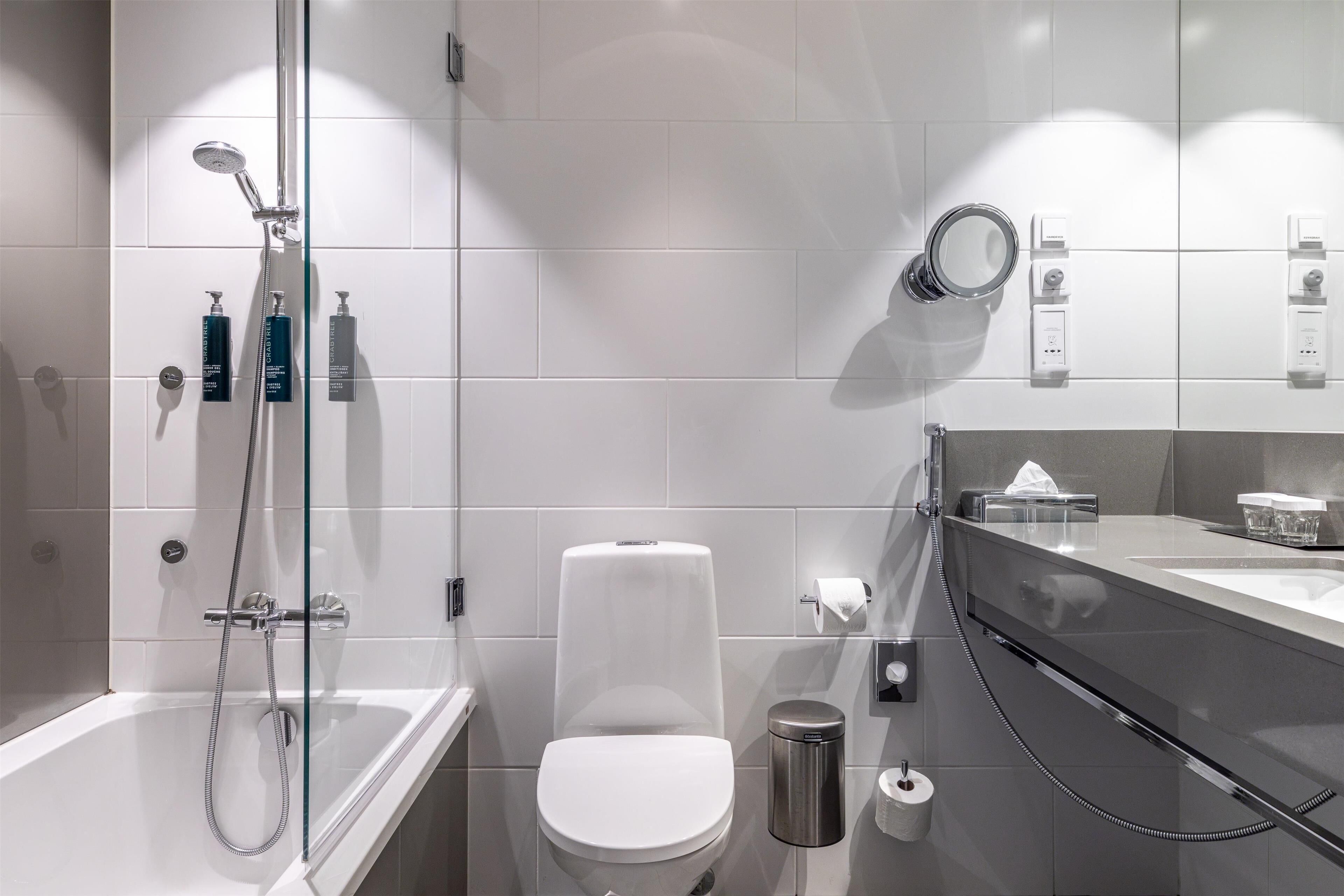 A modern bathroom with a glass-enclosed shower, a toilet, and a vanity with a mirror.
