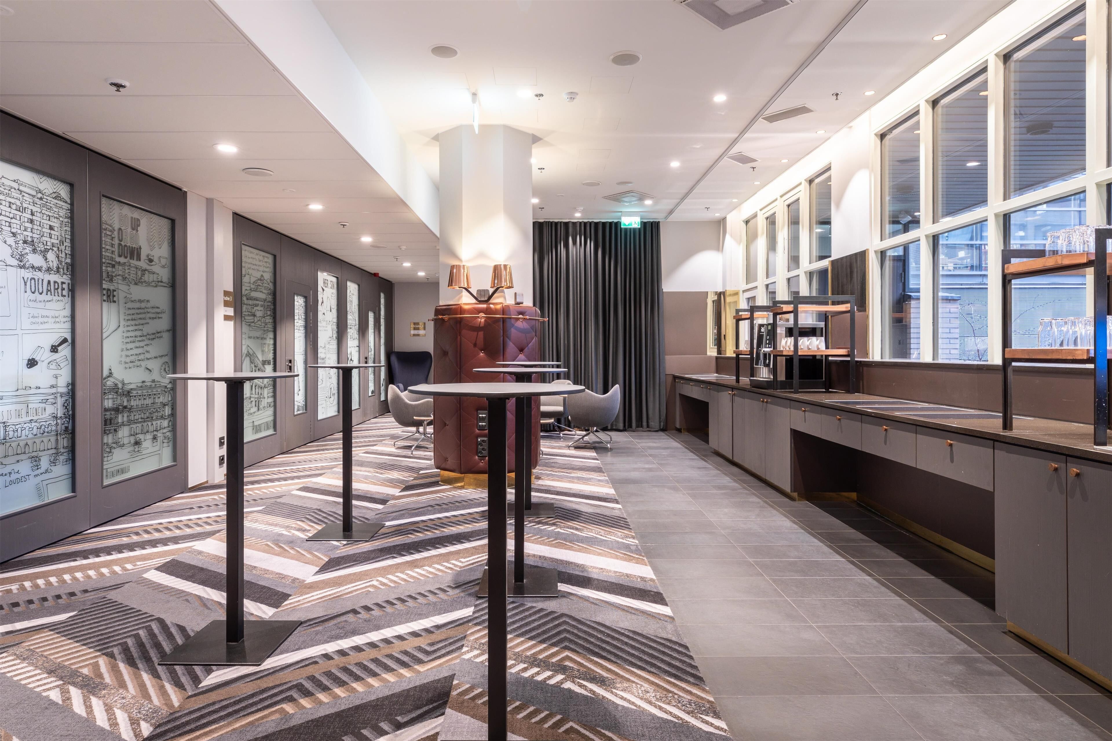 Een moderne hotel lobby met een kamerbreed tapijt, een centraal zitgedeelte en een receptiebalie.