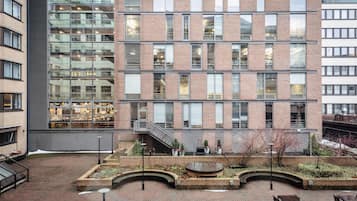Un edificio de varios pisos con un patio central que cuenta con una zona de estar circular y macetas con plantas.
