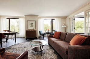A spacious living room with a sofa, armchairs, a coffee table, and a dining area. - Four Seasons Hotel Boston (Boston)