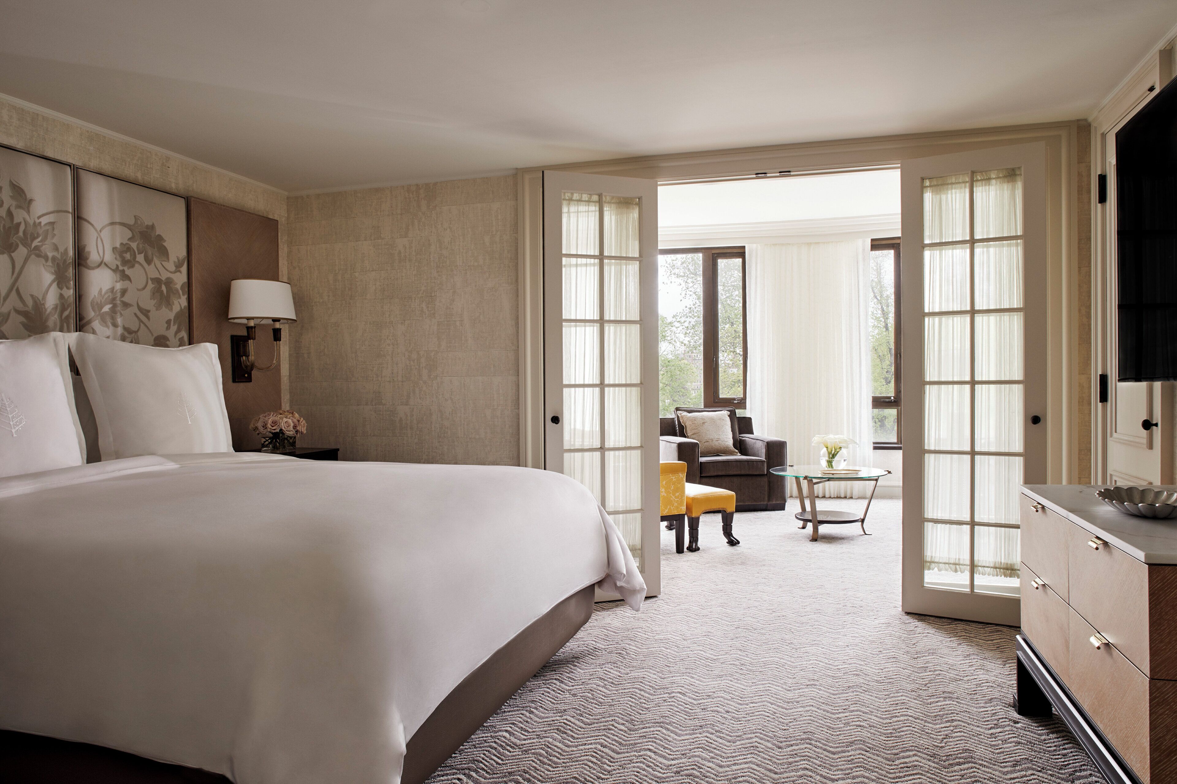 A hotel room with a large bed, a desk, a chair, and a view of the outdoors.