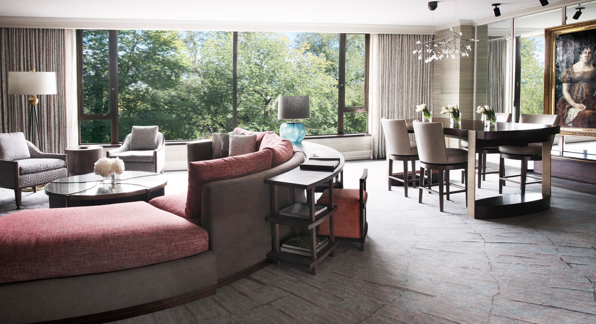 Un salon moderne comprenant un canapé, des fauteuils, une table à manger et une grande fenêtre donnant sur un paysage arboré.