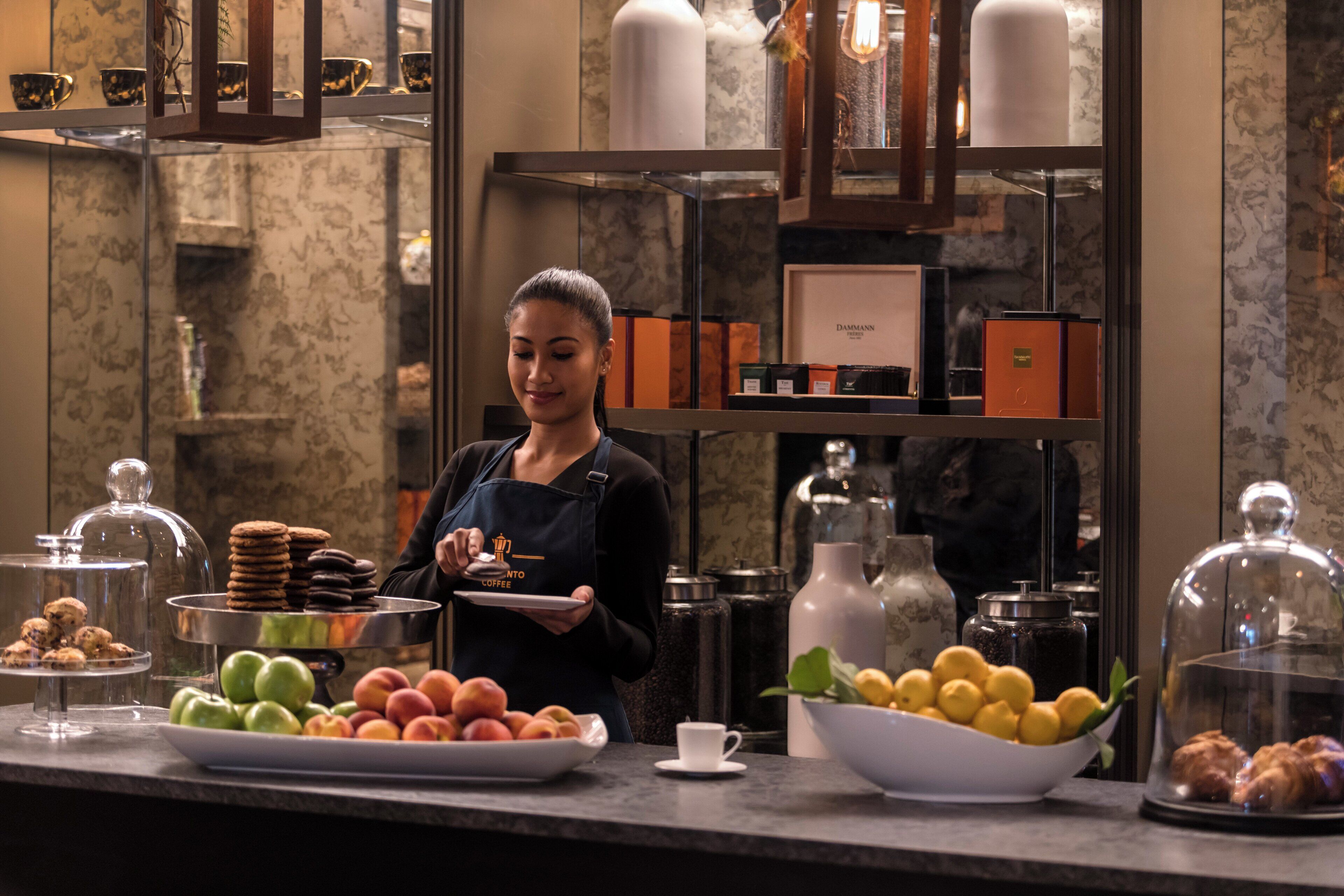 Un buffet proposant une variété de plats, notamment des fruits, des pâtisseries et un coin café.