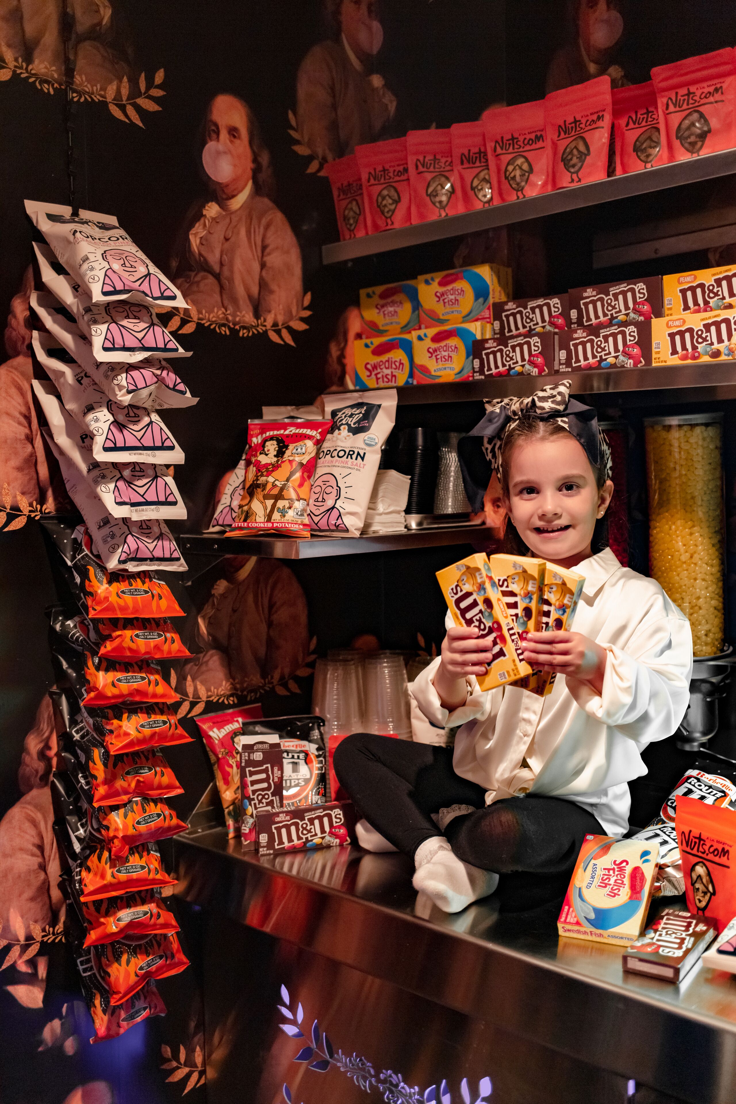 A child holding snack packets in front of a snack display.