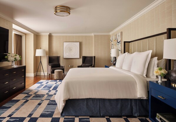 Habitación de hotel con una cama grande, un escritorio, una silla, un aparador y un televisor.