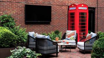 A brick wall with a red telephone booth and a flat-screen TV mounted on it.