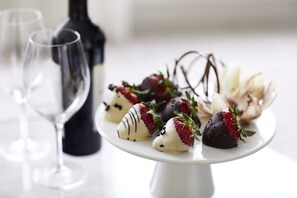 A white cake stand with chocolate-covered strawberries and a bottle of wine in the background. - Four Seasons Hotel Boston (Boston)