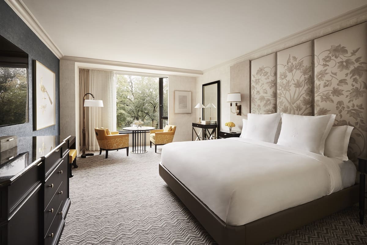 Ein Hotelzimmer mit einem großen Bett, einem Schreibtisch mit Stuhl, einem kleinen runden Tisch und einer Couch.