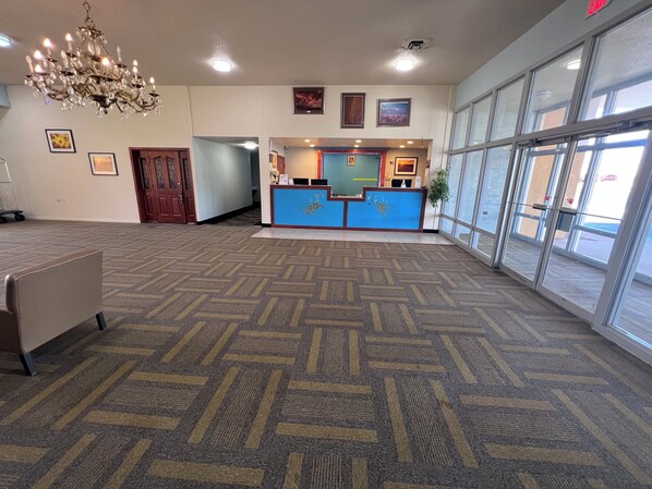 A spacious lobby with a patterned carpet, a reception desk, and a chandelier.