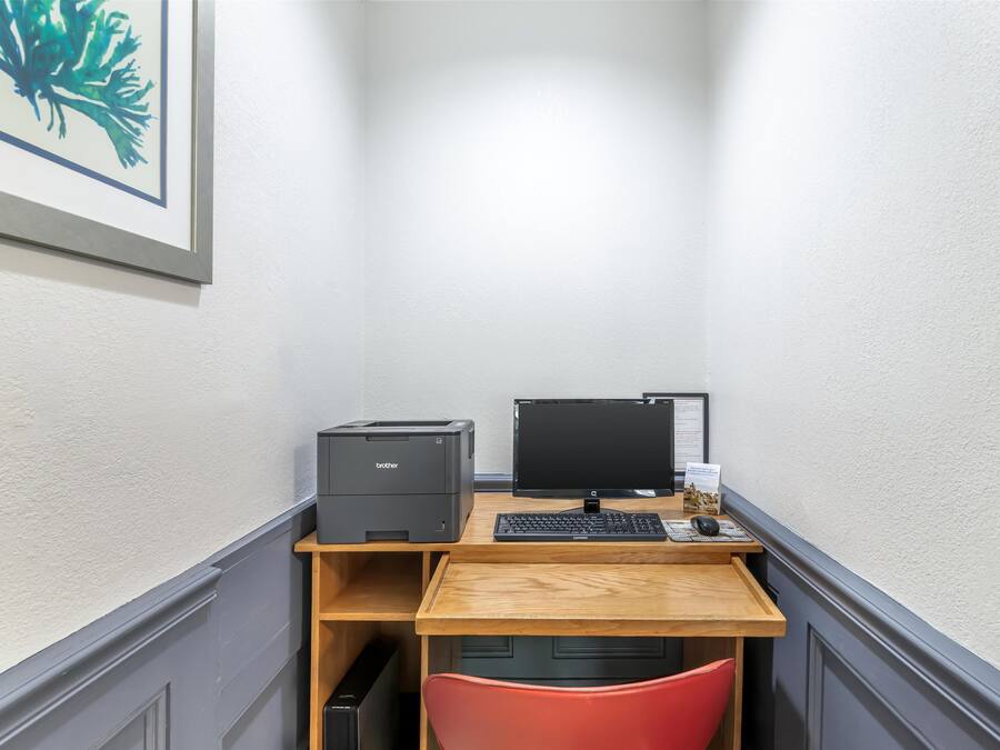 A small office space with a desk, two monitors, a printer, and a chair.