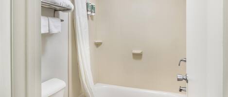 A bathroom with a bathtub, toilet, and shower curtain.