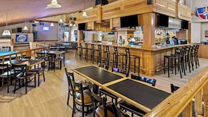 A spacious restaurant with wooden tables and chairs, a bar area, and a visible beer sign. - Best Western Tower West Lodge (Gillette)