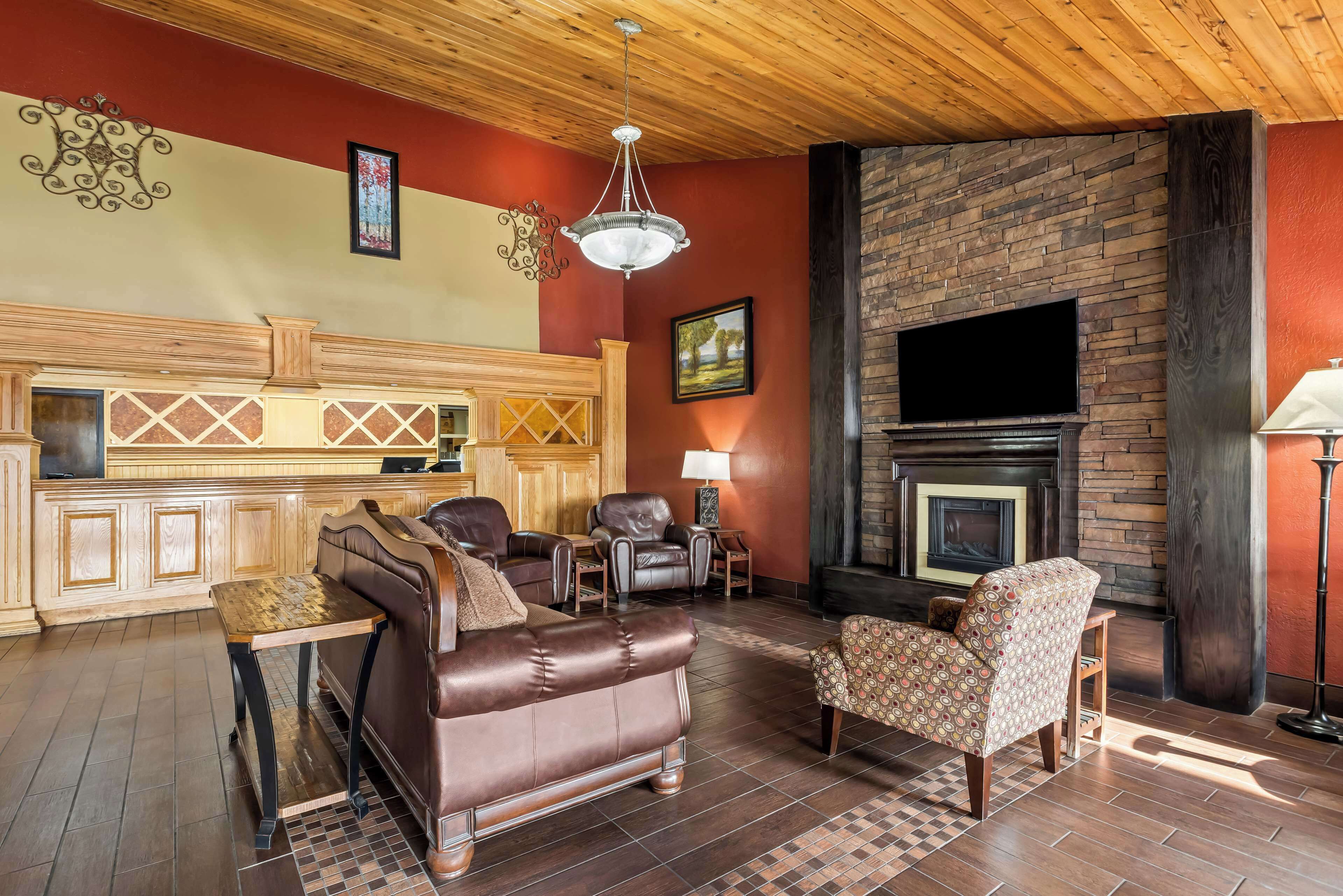 A cozy living room with a fireplace, leather sofas, and a TV mounted on the wall.