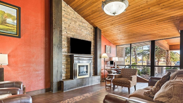 A spacious living area with leather sofas, a fireplace, and a large window offering a view of the outdoors. - Best Western Tower West Lodge (Gillette)