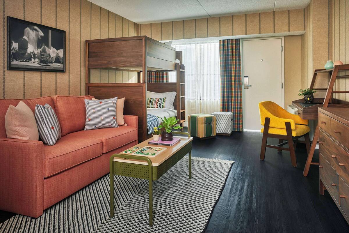 A cozy room with a bunk bed, a sofa, a desk, and a chair.