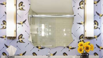 Baño con lavamanos, espejo y azulejos decorados con motivos de pájaros.