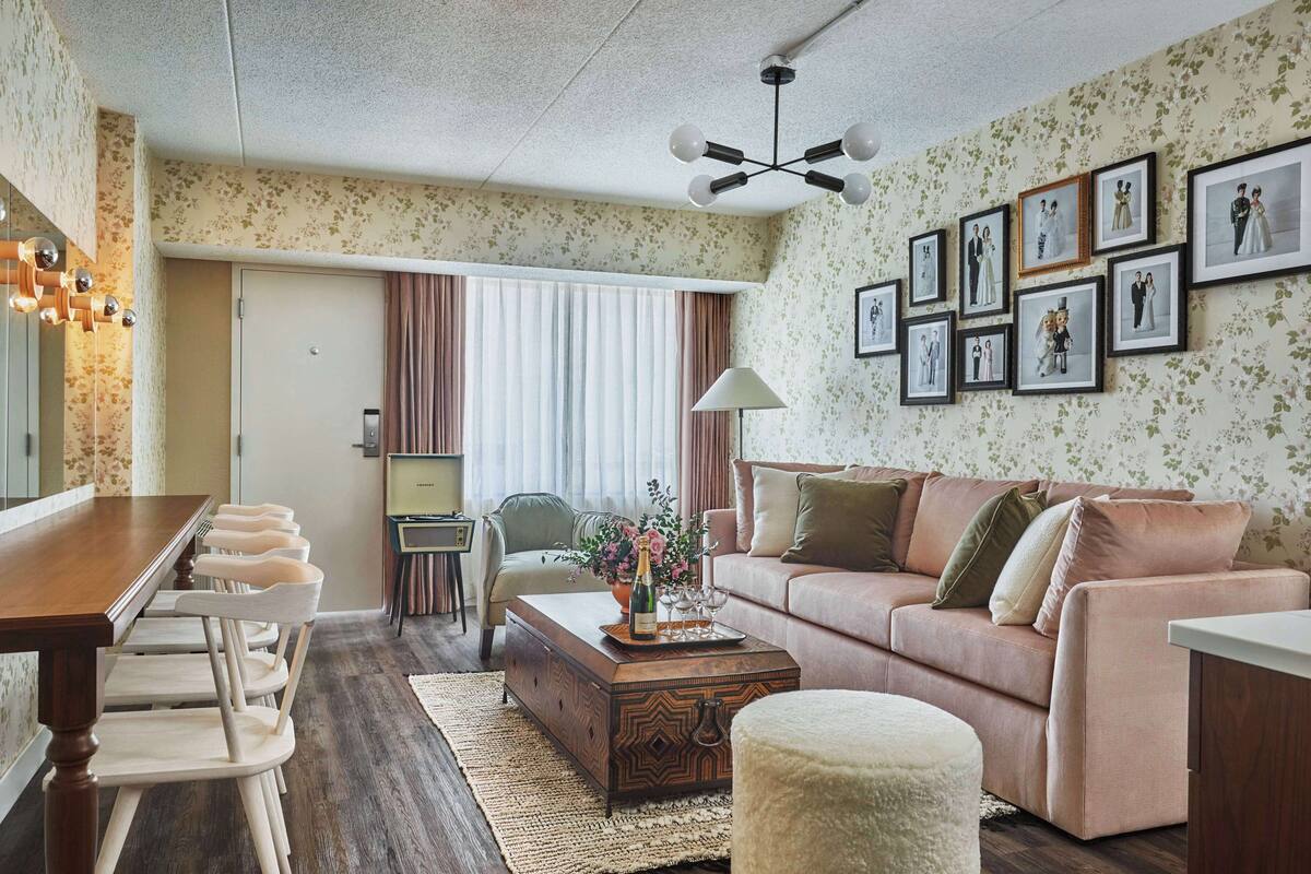 A living room with a wooden coffee table, a sofa, a dining table with chairs, and a TV.
