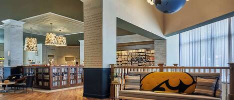 Una biblioteca amplia con estanterías, un rincón de lectura con sofá y un gran globo colgando del techo.