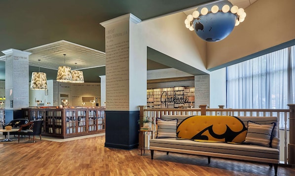 Una biblioteca amplia con estanterías, un rincón de lectura con sofá y un gran globo colgando del techo.
